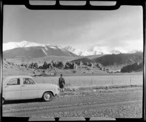 Car parked on the road in rural Canterbury, with Castle Rocks and Porters Pass in the background