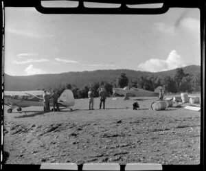 Fox Glacier airstrip, showing unidentified men and two aeroplanes on grass area