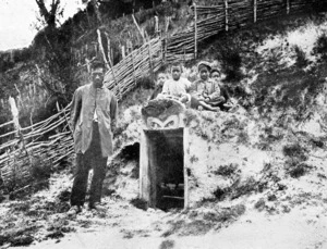 Unidentified Maori man and children, alongside a kumara storehouse on the East Coast