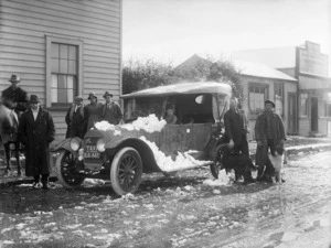 Group of people standing around a Jackson VII motor car, partially covered in snow
