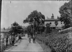 Narrow street in Wellington [Grant Road, Thorndon?] with large wooden houses and unidentified group