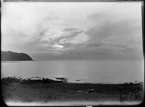 A scene with beach in foreground, headland at left, and light breaking through clouds, Tory Channel, Marlborough Sounds