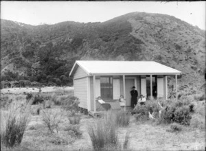 Wooden hut, with unidentified persons sitting on porch, [Marlborough Sounds?]
