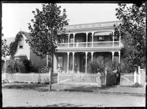 A two-storied wooden boarding house, possibly Wellington region, includes unidentified persons