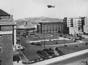 Robson, Edward Thomas : Area at front of Wellington Railway Station, with a biplane flying overhead