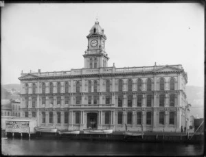 Wellington General Post Office seen from the water, including boats and advertisments for Wilson & Richardson Drapers, Outfitters and Importers, and S Danks & Sons Prass Founders & Coppersmiths, Plumbers & Gas Fitters