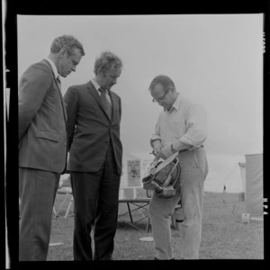 Member of Parliament, Duncan McIntyre, and another unidentified man being shown a chainsaw
