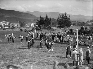 Young women playing netball and a group of spectators at the sideline