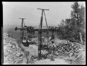 Top of aerial tramway with bucket of ore and Joseph Divis in foreground