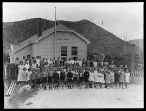 Group portrait of pupils and staff outside Waiuta School building
