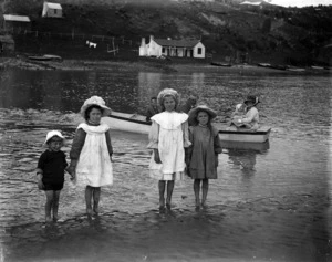 Four children standing on the sand, in shallow water