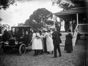 Bride and groom in their Model T Ford being farewelled by friends and family