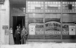 Four people standing outside the business of John Wilson & Co, Auckland