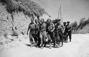 Evacuated New Zealand soldiers of transport RMT walk along a road with their possessions, Greece