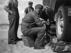 Soldiers from 1NZ Amm Coy working next to the wheel of a truck