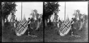 Unidentified family group with dog, raising the Union Jack on a home made flag pole in a cleared field, [Catlins district?}