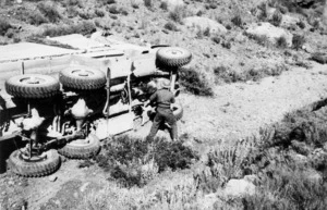A soldier of New Zealand Division Ammunition Coy rendering a truck useless before abandoning it to the enemy