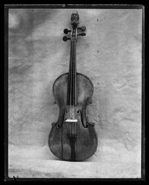 A studio photograph of an old cello instrument