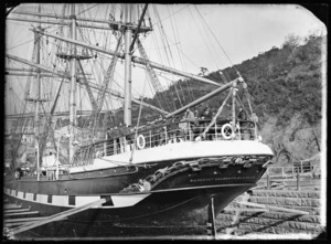 View of the stern of the sailing ship Margaret Galbraith in the graving dock at Port Chalmers, with crew members looking towards the camera.