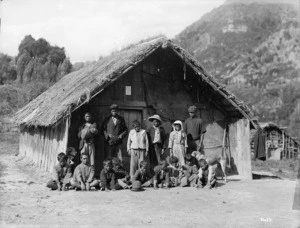 Unidentified Maori children alongside a whare