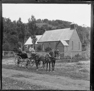 Unidentified man and woman in a horse-drawn buggy, with driver, outside a wooden Anglican church, Leith Valley, Dunedin