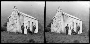 Men outside a wooden cottage during a rabbit hunting expedition, Murdering Beach, Otago