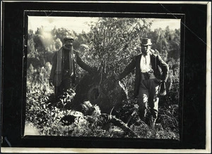 Unidentified Maori men, with disused corn grinding stone