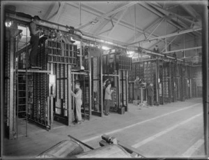 Unidentified men installing components in a telephone exchange, location unidentified