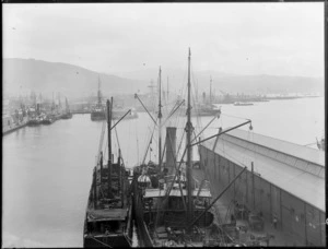 Wellington wharves, foreground shows a ship that is being loaded with goods from horse-drawn carts and Wellington Harbour Board shed