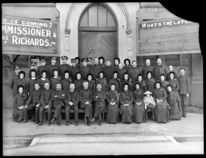Salvation Army group, outside the front entrance of an unidentified stone building which has message boards attached, [Christchurch?]