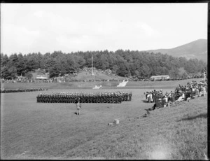 Military ceremony, showing infantry marching in a park with spectators at perimeter and dignitaries to right, [Christchurch?]