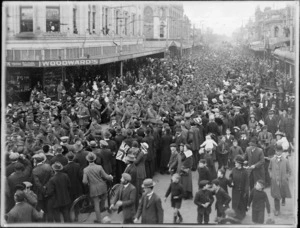 World War I soldiers marching down Colombo Street with crowd waving flags, outside Woodward's shop, Christchurch City