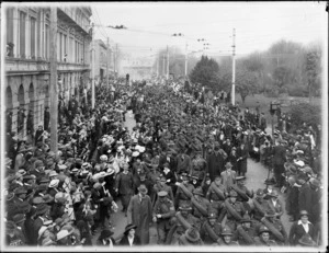 Crowd gathered in Colombo Street waving flags, with photographer getting off step-ladder, Victoria Square, Christchurch, to farewell World War I troops