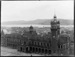 Dunedin Railway Station, with The Alliance Bee Supplies Co Ltd imperial bee blended honey business behind, and wharf area and harbour beyond