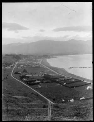 Seaside resort town of Kaikoura looking north, showing the Esplanade and Torquay Street with houses and fields to commercial buildings mid-view, farmland and seaward Kaikoura Mountain Range beyond