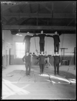 Gymnastics team in a pose, three by three on shoulders, probably in Christchurch