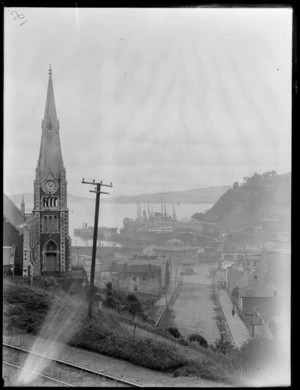 Port Chalmers Harbour, Dunedin, showing local Presbyterian Church with steeple tower and Mount Street with band rotunda, to the wharf area with ships and commercial buildings, John Mill Co Ltd Stevedores