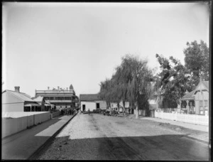 Street scene in Gisborne, showing a portion of a building being moved down the street by bullock team, with onlookers outside a hotel