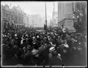 View of people welcoming home invalided World War I soldiers with street parade, showing cars with troops being mobbed by crowd, Wellington Town Hall