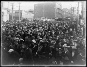 View of Lower Cuba Street, showing a procession of people behind a barrier, near Wellington Harbour, to welcome home invalided World War I soldiers, street signs with advertising in background 'The British United Shoe Machinery Co'