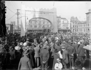 Peace celebrations in Cathedral Square, Christchurch, after World War I featuring a crowd watching a parade of sailors under an arch labelled 'Heligoland Bight'