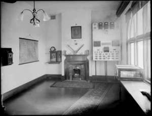 Fire brigade watch house, showing fireplace, fire instruments and map on the wall, probably Christchurch