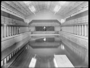Interior of the Christchurch Municipal Baths building, with a man standing alongside the pool