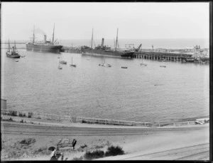 Ships docked at the wharf, Timaru, with a tugboat and small boats in the foreground