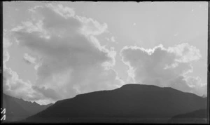 A mountain peak in shadow, with sunlight and clouds overhead, [Fiordland National Park, Southland District?]