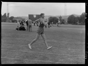 An unidentified man during a sports event [walking?], Dewar Sheild Athletics, Hutt Park, Gracefield, Lower Hutt City, Wellington Region