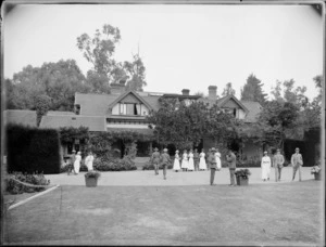 Unidentified soldiers and nurses standing on a lawn outside a two-storied wooden house, Christchurch