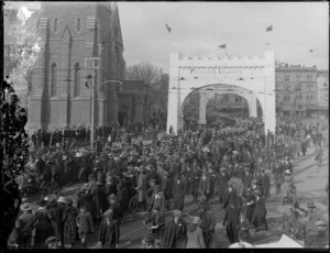 Peace celebrations in Cathedral Square, Christchurch, after World War I with parade of sailors and crowd, including arch labelled 'Falkland Islands'
