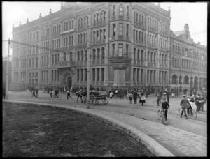 The Christchurch Press Company building, with a group of people in the streets, horse, cart and bicycles