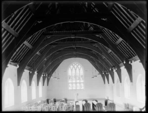 Church interior, showing ceiling beams, pews, chairs and glass stained window